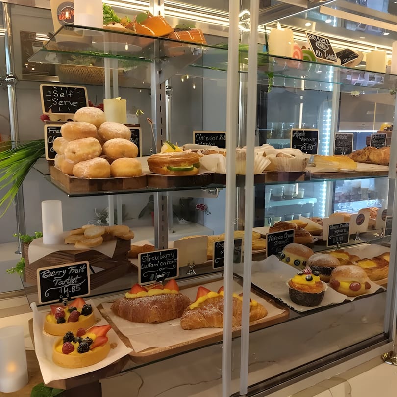 A glass display case at Paris Bánh Mì filled with various Vietnamese pastries, tarts, and donuts.