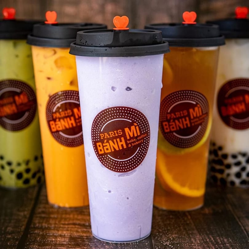 Five Paris Bánh Mì boba drinks in various colors, including taro, mango, and matcha.