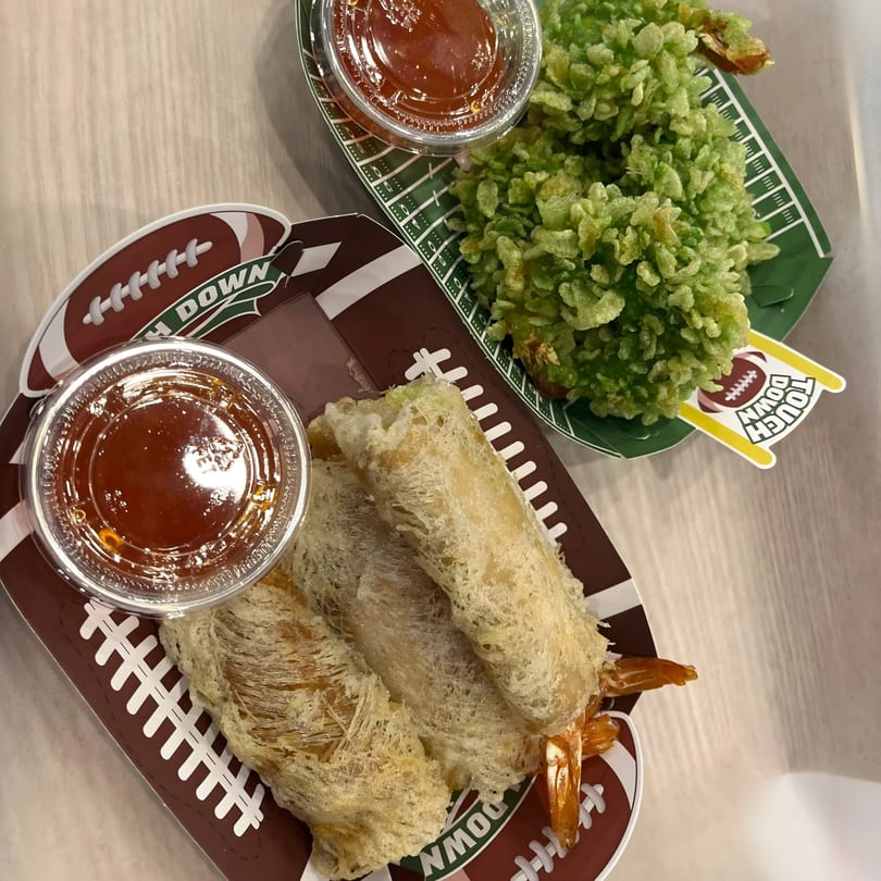 Crispy shrimp spring rolls and green fried shrimp served in football-themed containers with dipping sauce.